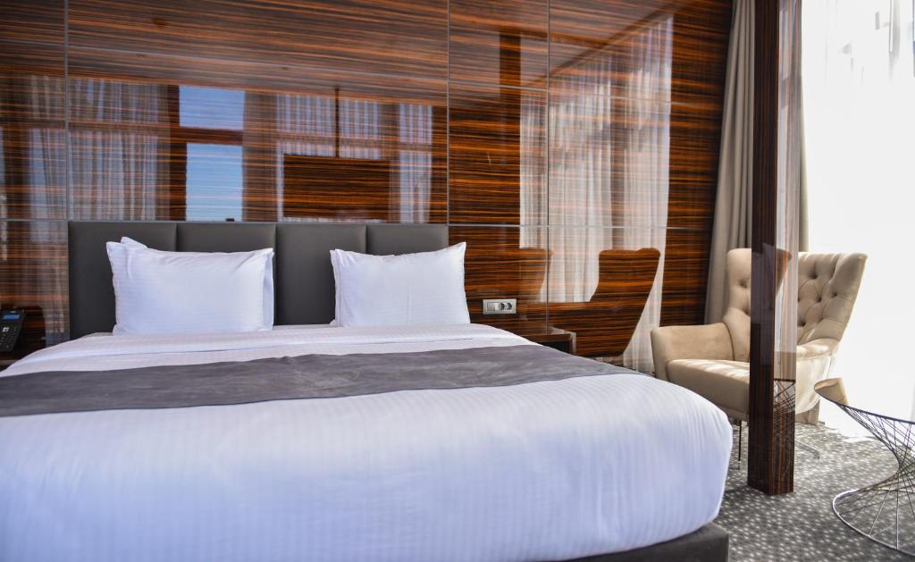 Moderns viesnīcas numurs ar ērtu gultu, elegantām mēbelēm un lieliem logiem, kas nodrošina daudz dabiskās gaismas.