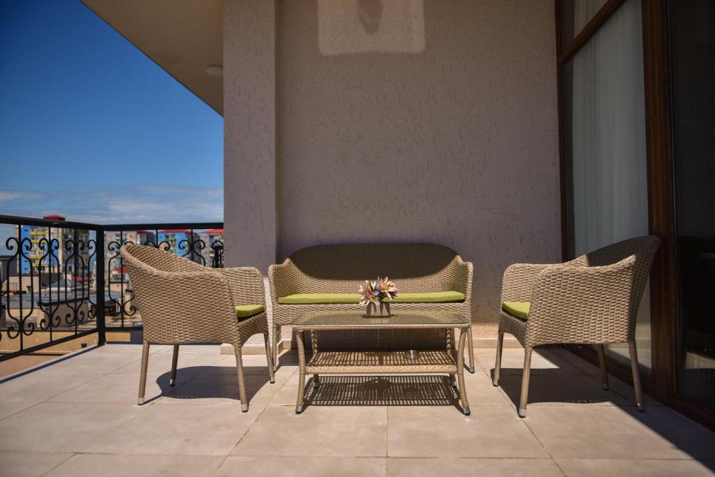 Mūsdienīgs balkons ar vītinātām mēbelēm un zaļiem spilveniem, kas nodrošina komfortablu atpūtu. Ideāla vieta relaksācijai un baudīšanai.