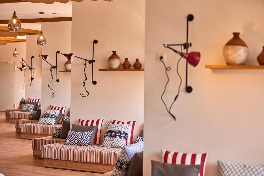 Mūsdienīgs interjers ar ērtām dīvāniem, dekoratīvām spilveniem un apgaismojuma elementiem, kas rada relaksējošu atmosfēru. Uz plauktiem redzami keramikas trauki, kas papildina telpas dizainu.