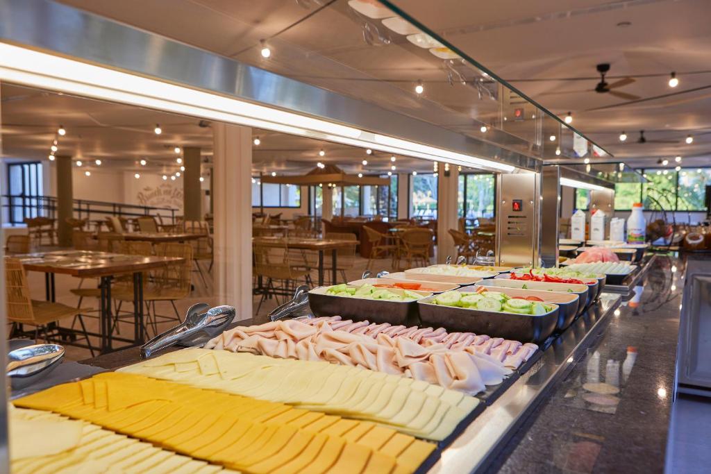 Salātu bārs ar dažādiem dārzeņiem un gaļas šķēlēm, kas izvietots modernā un gaišā restorānā. Interjers ir plašs un ērts, ar koka mēbelēm un dabisku apgaismojumu.