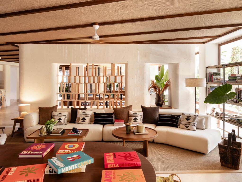 Mūsdienīgs un stilīgs viesistabas interjers ar ērtu dīvānu, dekoratīvām spilveniem un krāsainām grāmatām uz galda. Gaisīga atmosfēra ar dabīgu apgaismojumu un zaļumiem.