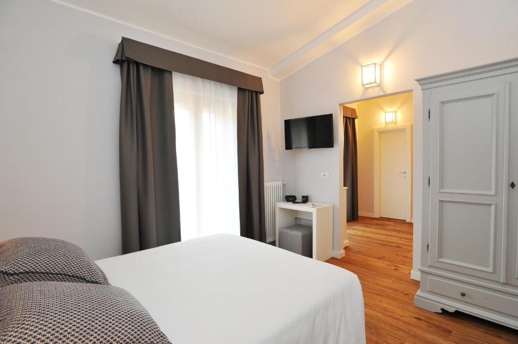 Mūsdienīgs guļamistabas interjers ar gaisīgām aizkariem, televizoru un elegantu skapi. Koka grīda piešķir siltumu, radot mājīgu atmosfēru.