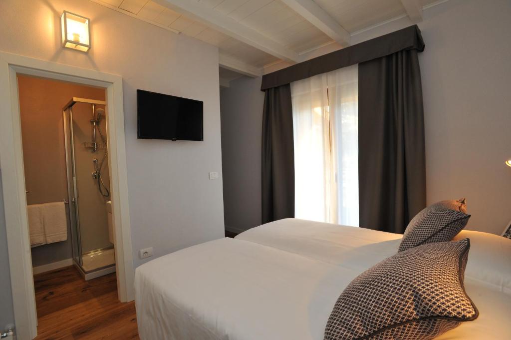 Mūsdienīga guļamistaba ar divguļamo gultu, televizoru un piekļuvi vannas istabai. Interjeru papildina gaiši toņi un eleganti aksesuāri.