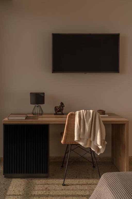 Mūsdienīgs rakstāmgalds ar melnu lampu, dekoratīvu figūru un siltu segu, kas uzkārta uz krēsla, radot viesmīlīgu un funkcionālu telpu.