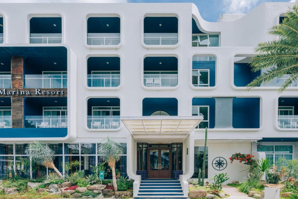 Sugar Marina viesnīcas modernā arhitektūra ar balkoniem un dārza ainavu.