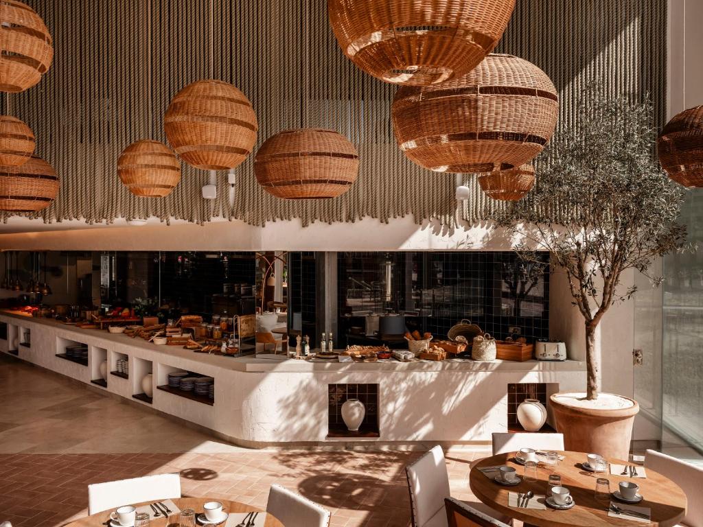 Moderns restorāns ar elegantiem ratiņu lampām, gaišu interjeru un bufetes staciju, kas piedāvā dažādus ēdienus. Interjerā ir arī zaļie augi, radot patīkamu atmosfēru.