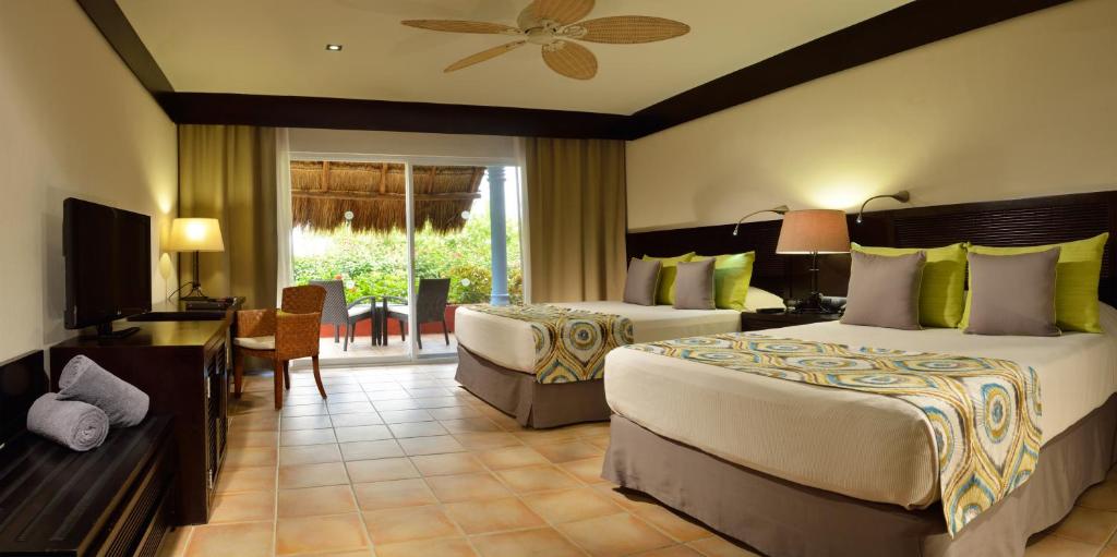 Grezns viesnīcas numurs ar divām gultām, televizoru un terasi ar skatu uz dārzu. Interjers ir moderns, ar siltām krāsām un ērtu mēbelējumu.