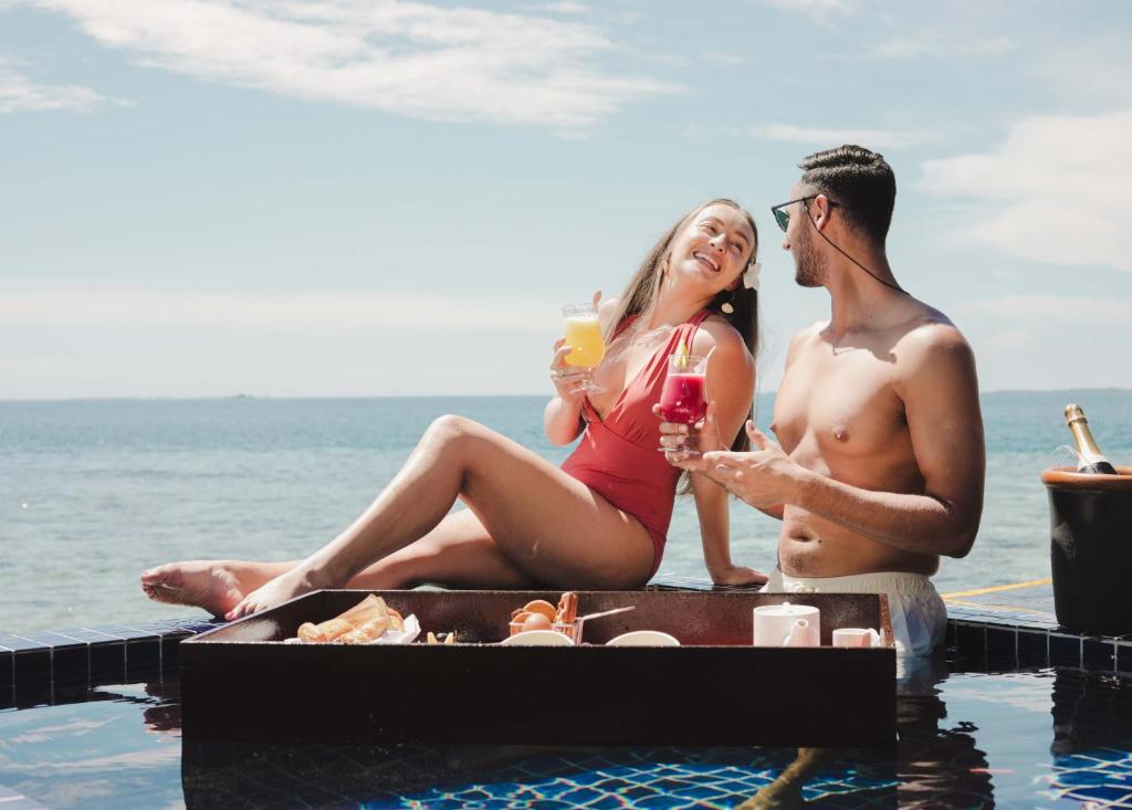 Jaunā pāra romantiska brīvdiena pie baseina ar kokteiļiem un skaistu skatu uz jūru. Ideāla atpūta un laika pavadīšana kopā.