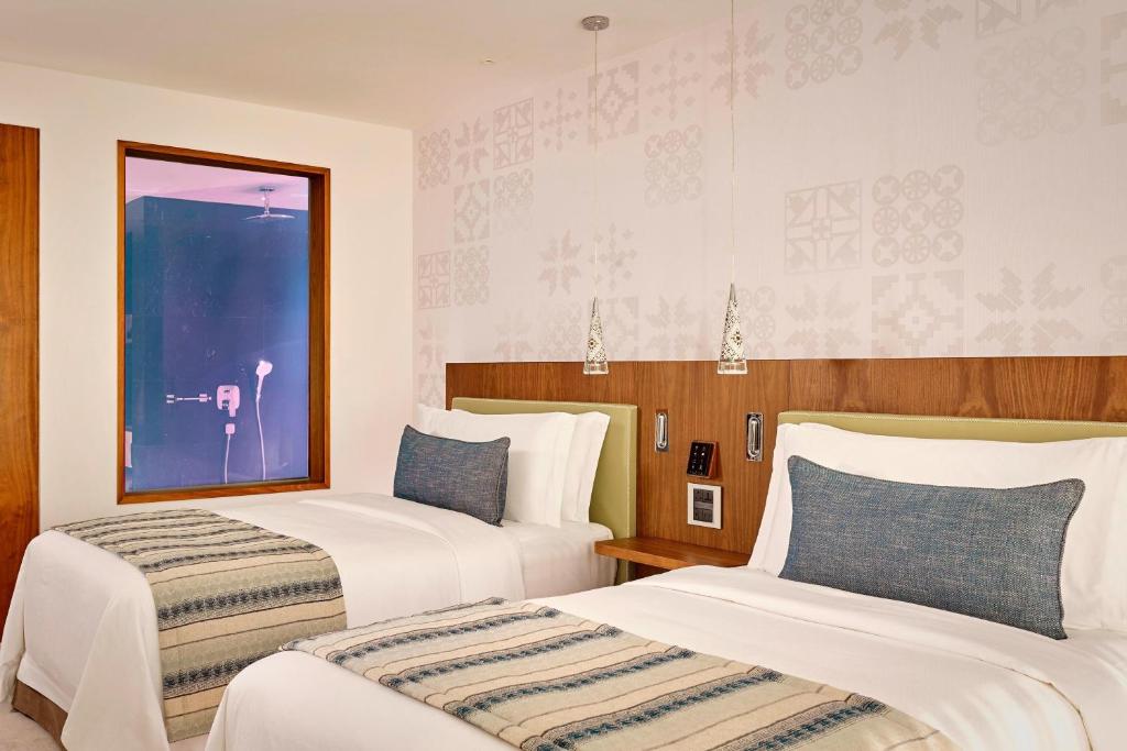 Mūsdienīgs viesnīcas numurs ar divām gultām, dekorēts ar koka un tekstila elementiem, kā arī ar mūsdienīgu vannasistabas skatu. Numura sienas rotā stilizēti raksti, radot mājīgu atmosfēru.