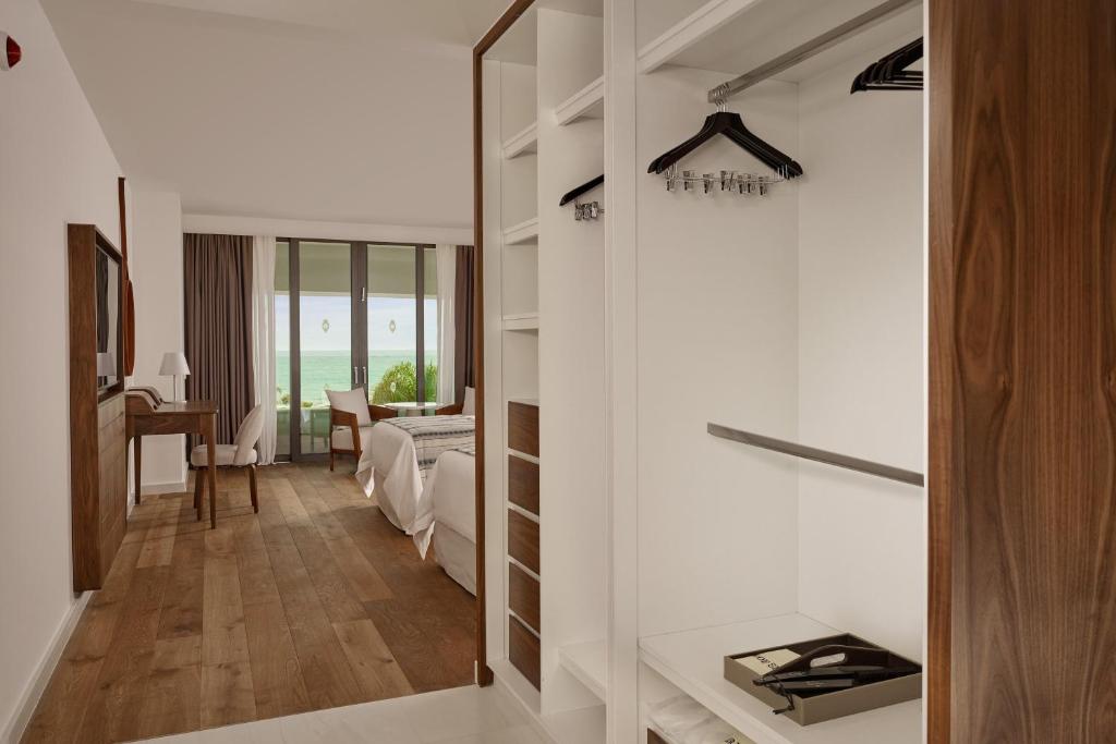 Mūsdienīgs viesnīcas numurs ar koka grīdu, plašu skatu uz jūru un elegantu skapīti, kurā ir pakaramie un piederumi. Interjerā ir arī rakstāmgalds un ērti krēsli.