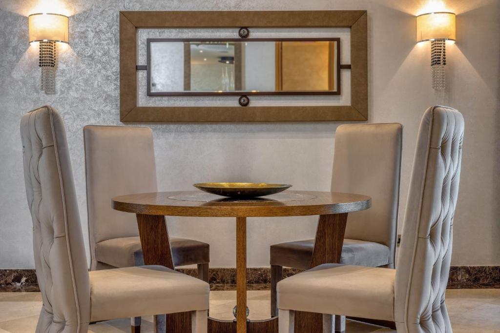 Elegants galds ar četriem krēsliem un spoguli, kas pievieno modernu pieskārienu telpai. Interjers izceļas ar neitrālām krāsām un mūsdienīgu dizainu.