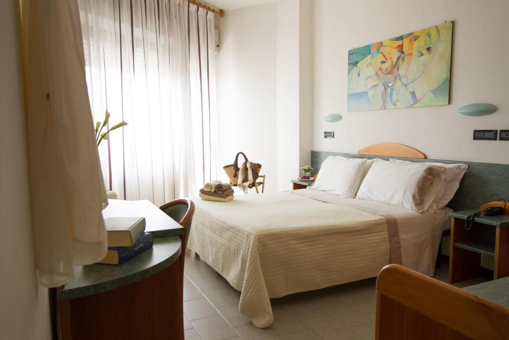 Mūsdienīgs viesnīcas numurs ar divguļamo gultu, elegantu dekori un gaisīgu atmosfēru. Telpā ir koka mēbeles, gaismas aizkari un gleznas uz sienām.