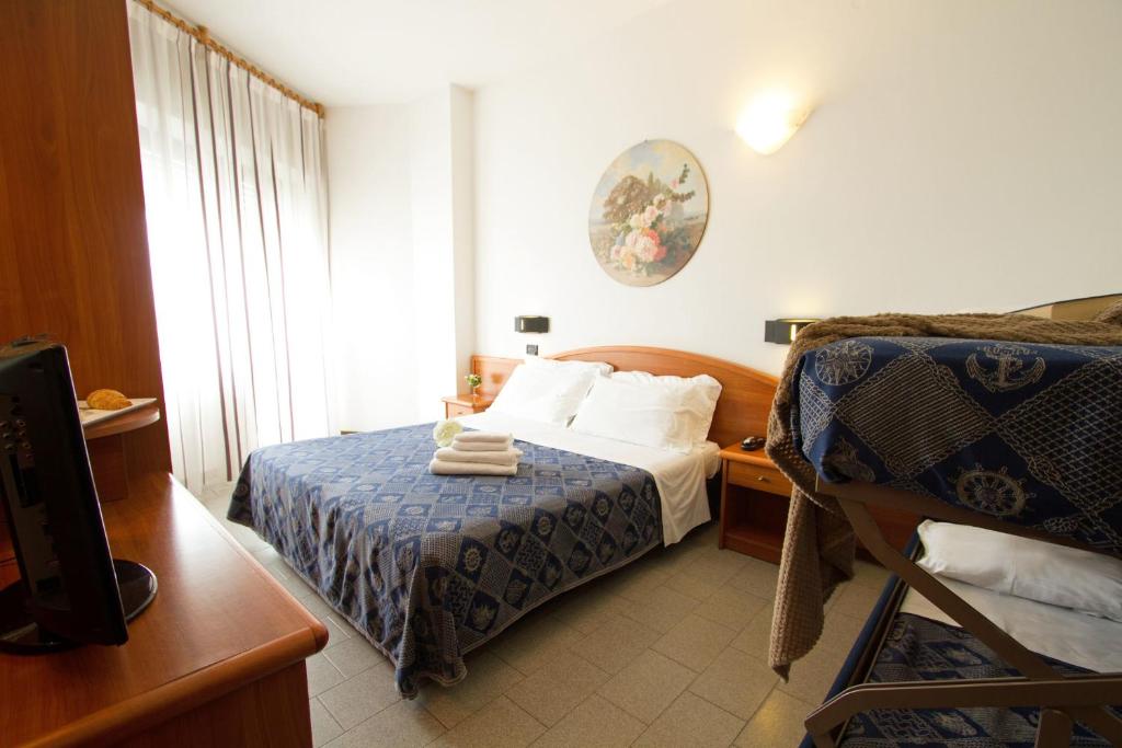 Mūsdienīga viesnīcas istaba ar divguļamo gultu un bunkuru, kas iekārtota ar siltām krāsām un elegantu interjeru. Logs ļauj gaismai ieplūst telpā, radot patīkamu atmosfēru.