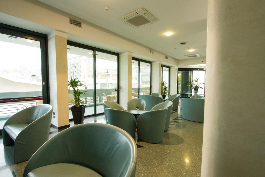 Mūsdienīgs un gaišs kafijas stūrītis ar ērtiem krēsliem un lielām logu vitrīnām, kas nodrošina dabisko apgaismojumu. Telpā ir zaļas augu dekorācijas, kas piešķir patīkamu atmosfēru.