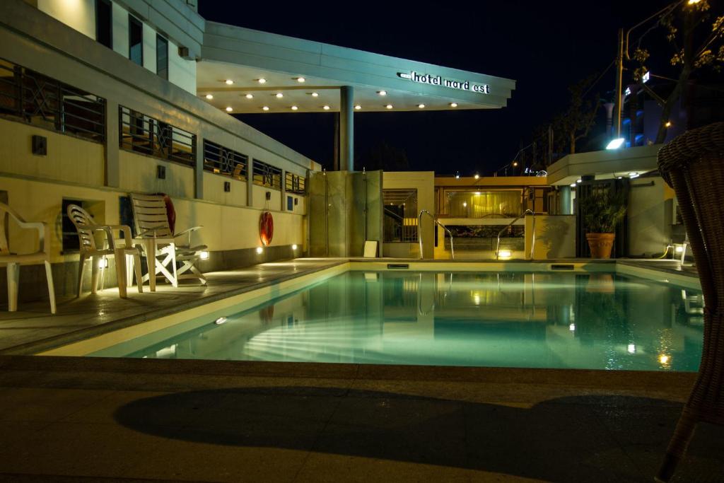 Baseins ar apgaismojumu viesnīcas "Mord Est" teritorijā naktī, radot relaksējošu atmosfēru. Apvidū redzami krēsli un augi, kas papildina dizainu.