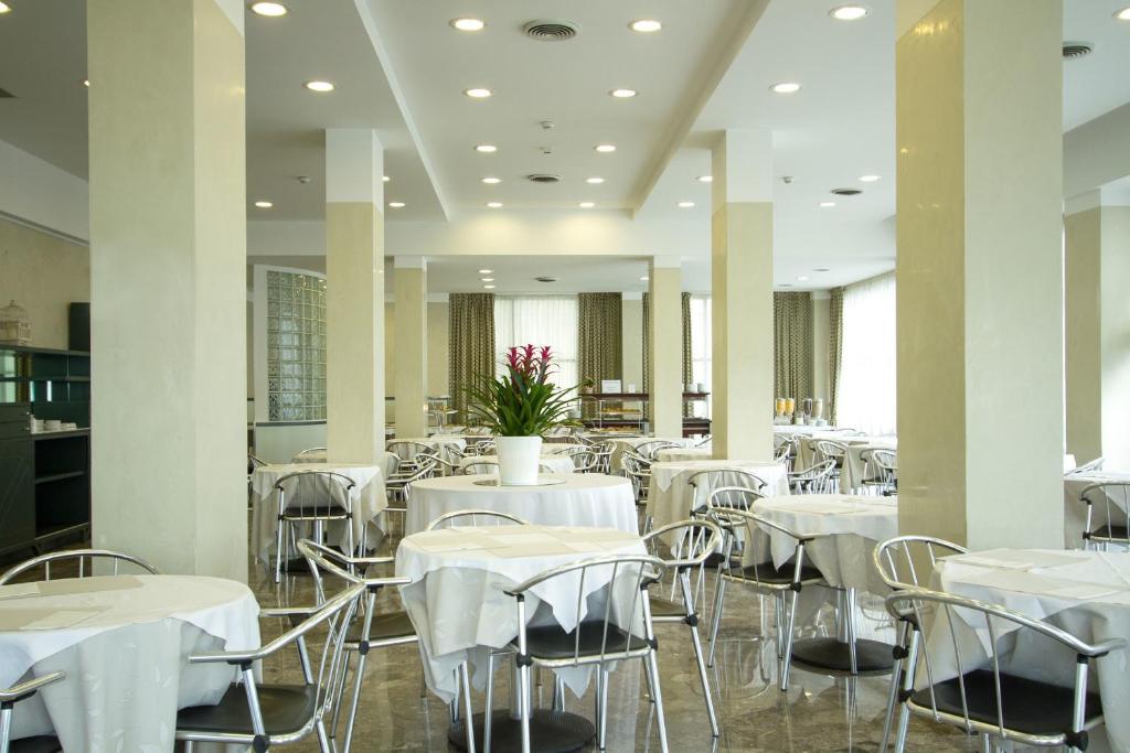 Mūsdienīgs restorāna interjers ar elegantiem galdiem un krēsliem, apgaismots ar mīkstu gaismu un dekorēts ar zaļām augiem. Ideāls vieta relaksācijai un maltītēm.