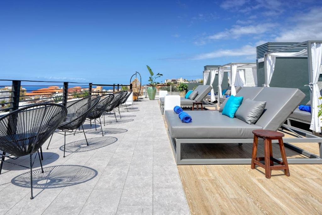Hovima Suite Costa Adeje jumta terase ar skatu uz okeānu un sauļošanās krēsliem.