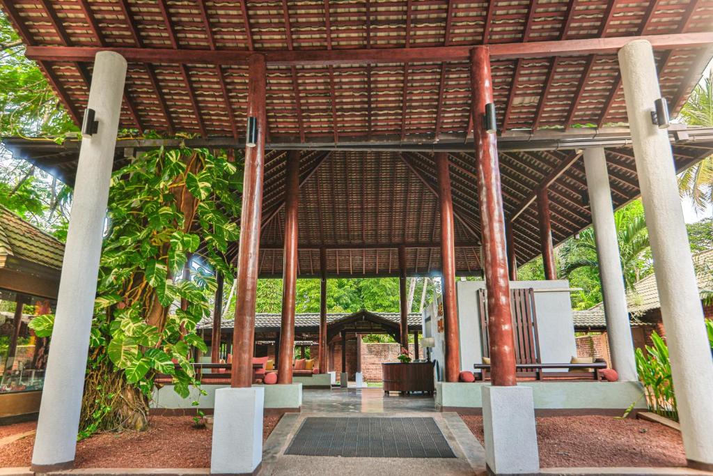 Mūsdienīga viesnīcas ieeja ar koka kolonām un jumtu, apzaļumota ar augiem un zālēm. Svaigs un viesmīlīgs noskaņojums, kas aicina apmeklētājus.