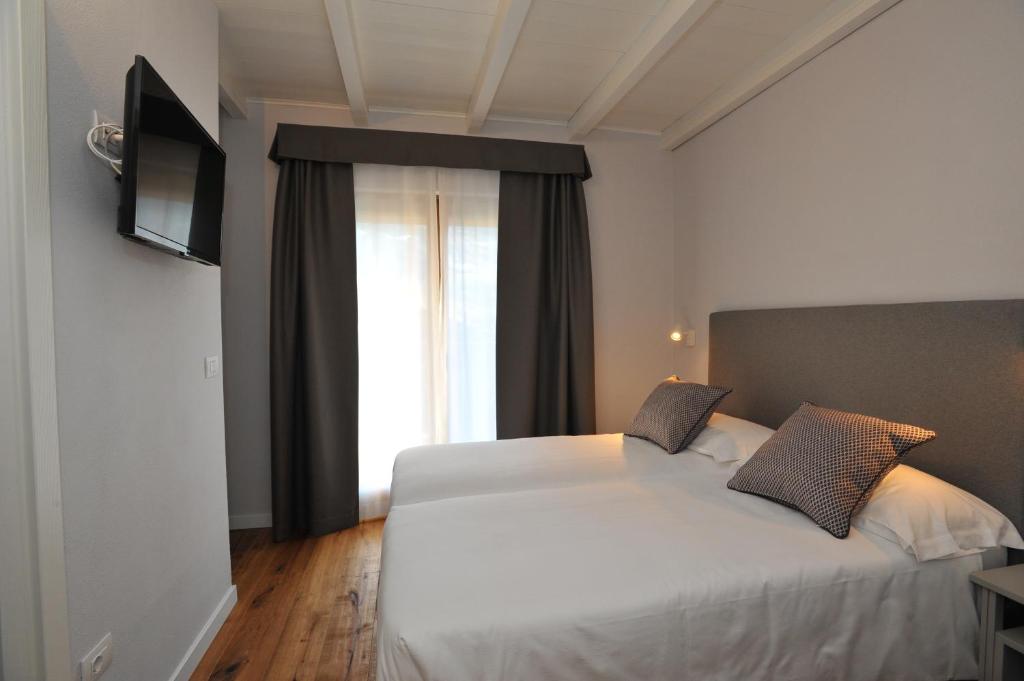 Moderns viesnīcas numurs ar divām gultām, televizoru un lieliem logiem, kas nodrošina dabisko apgaismojumu. Eleganti interjera elementi un koka grīda rada mājīgu atmosfēru.