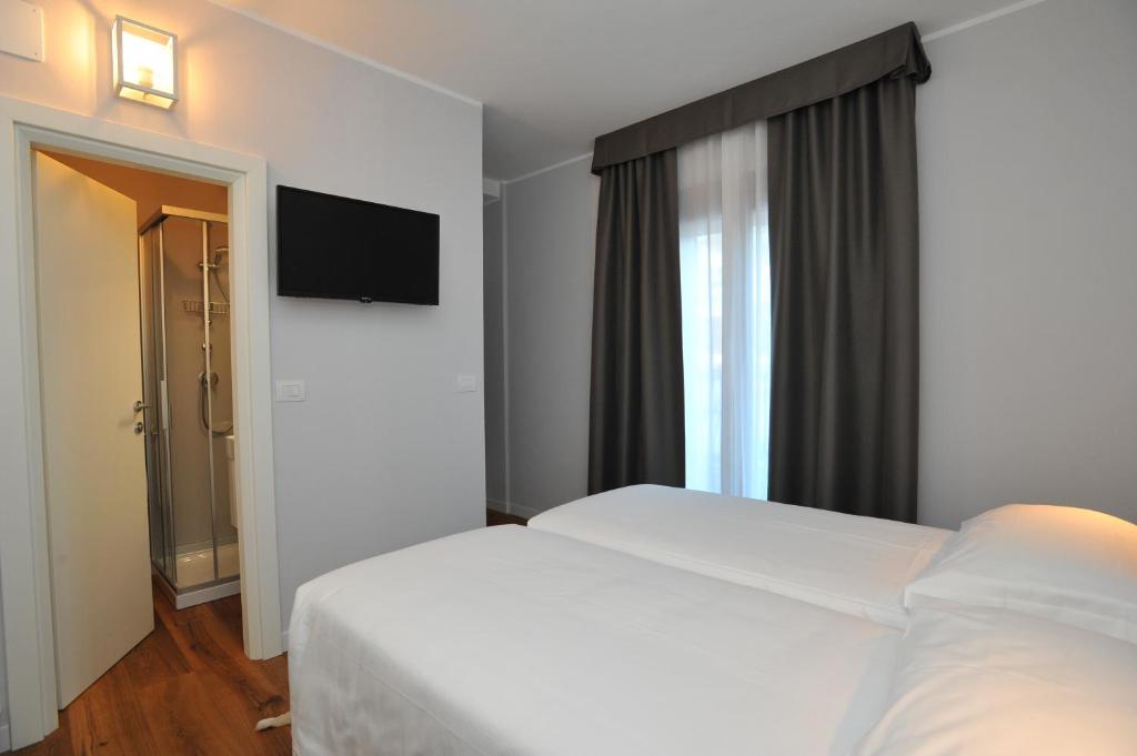 Mūsdienīga viesnīcas numura iekārtojums ar divām gultām, televizoru un dušas kabīni. Telpa ir gaiša un eleganta, ar logiem, kas nodrošina dabisko apgaismojumu.