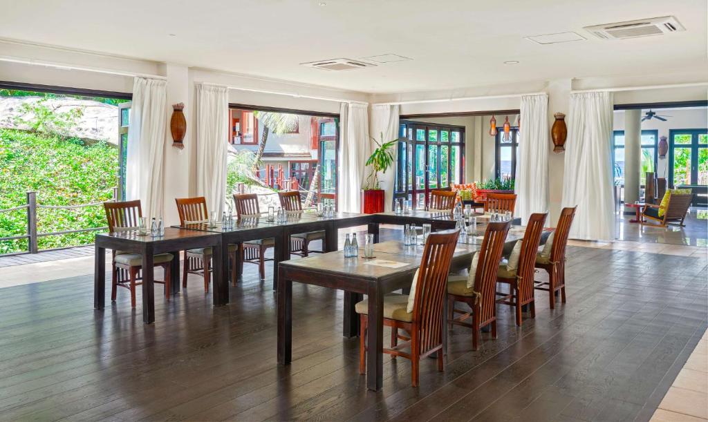 Mūsdienīgs, gaišs sapulču telpa ar koka galdu un krēsliem, kas piedāvā skatu uz dabu caur lielajiem logiem. Telpā ir daudz gaismas un augi, radot relaksējošu atmosfēru.