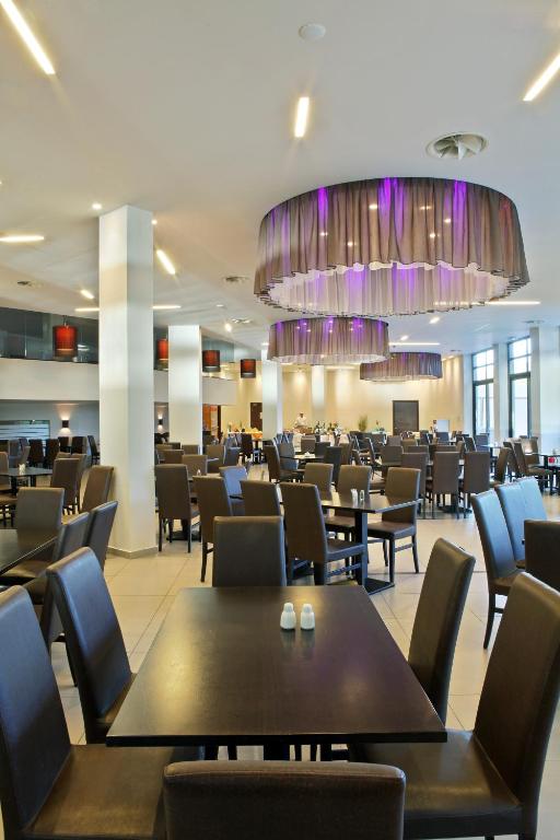 Mūsdienīgs restorāns ar elegantiem melnajiem galdiem un krēsliem, apgaismots ar stilīgām lampām. Telpas interjers ir gaišs un plašs, radot patīkamu atmosfēru.