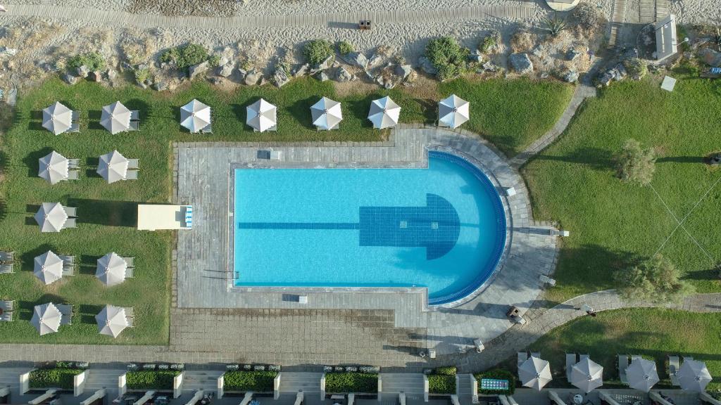 Aquila Rithymna Beach viesnīcas baseins ar sauļošanās gultām piekrastē.