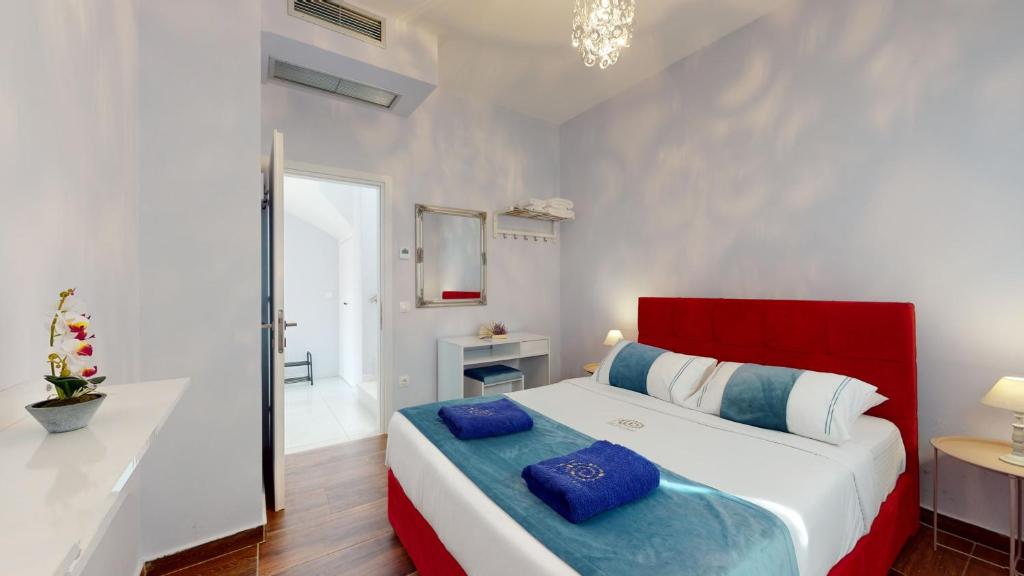 Mūsdienīga guļamistaba ar sarkano gultu, zilu gultas veļu un elegantu apgaismojumu. Telpā ir izsmalcināts dekors un ērts dizains, kas rada relaksējošu atmosfēru.