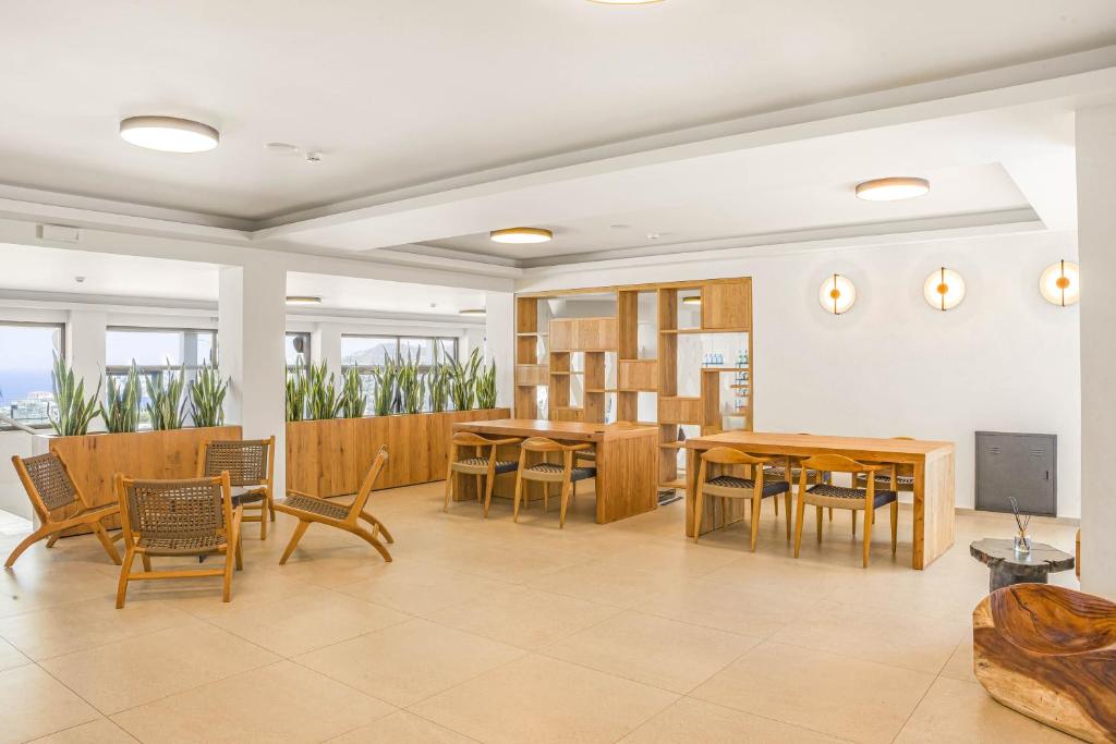 Panorama Village Hotel gaišā atpūtas zona ar koka mēbelēm un augiem.