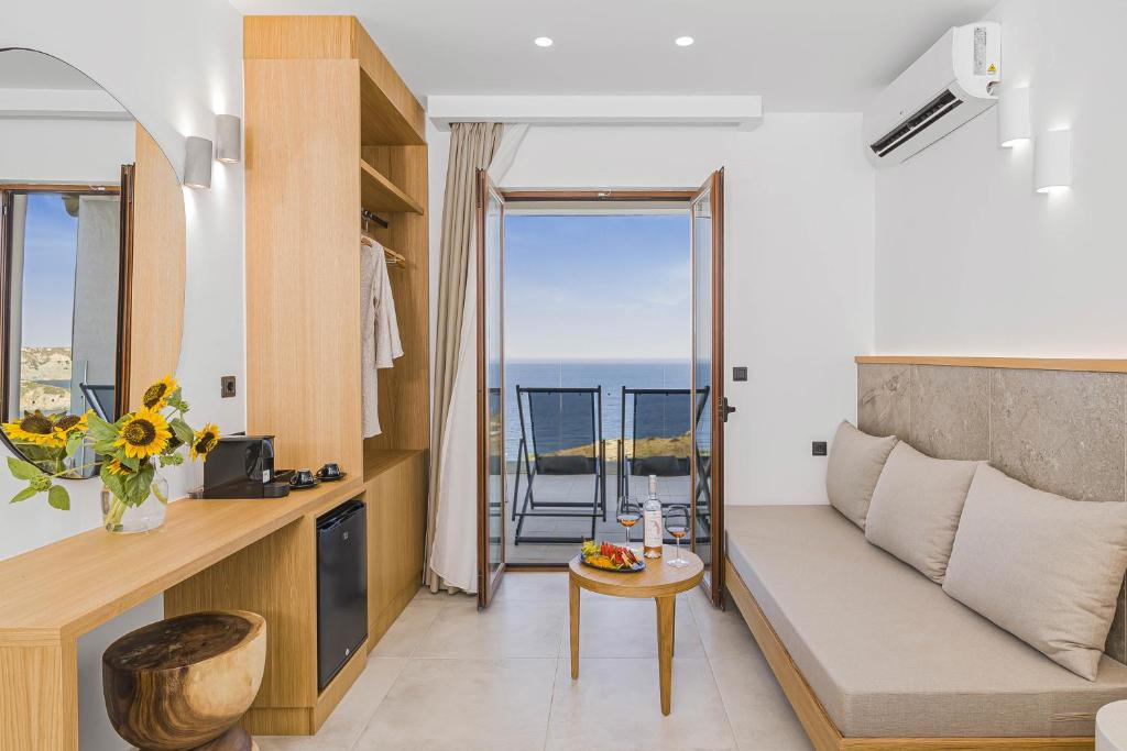 Gaišs un moderns Panorama Village Hotel numurs ar koka mēbelēm, atpūtas zonu un atvērtām balkona durvīm ar skatu uz jūru.