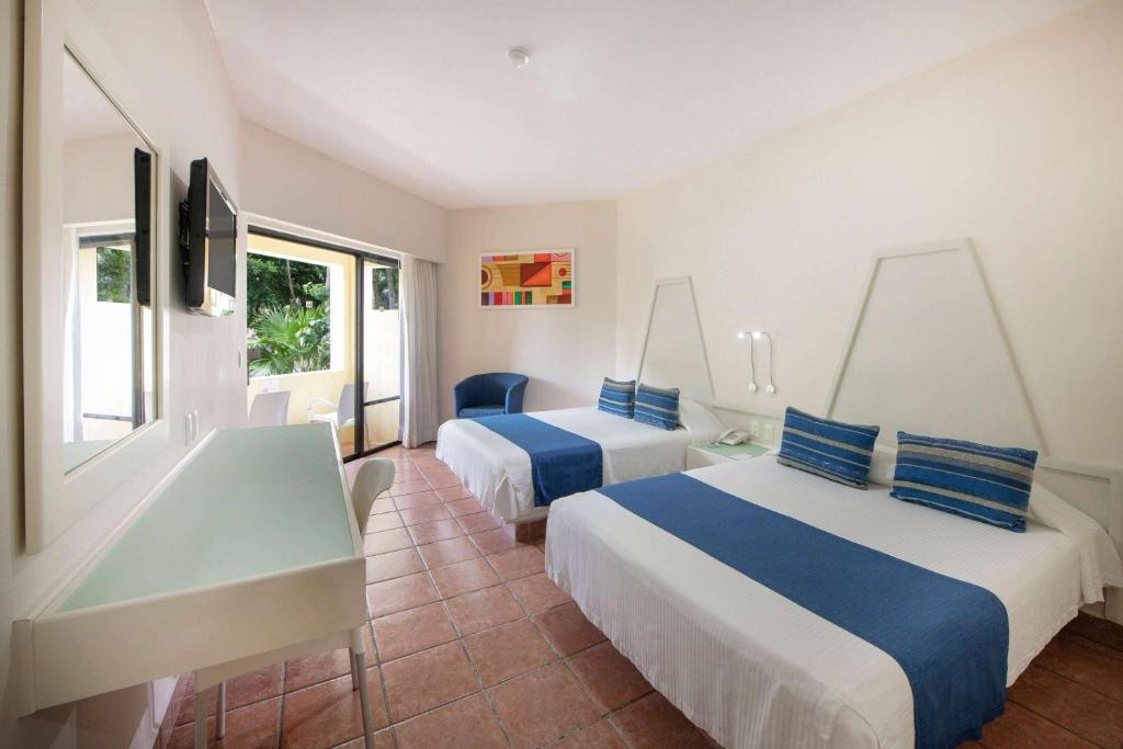 Mūsdienīga viesnīcas numura iekārtojums ar divām gultām, televizoru un rakstāmgaldu. Logi ved uz dārzu, radot patīkamu gaisotni.