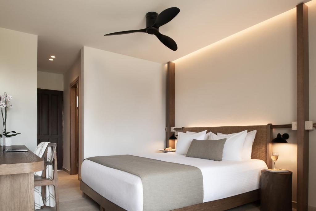 Mūsdienīgs viesnīcas numurs ar ērtu gultu, koka mēbelēm un modernu ventilatoru, radot relaksējošu atmosfēru. Numurā ir arī rakstāmgalds un ziedi dekoratīvā podā.