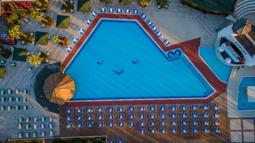 Lidostas baseins ar saulessargiem un atpūtas krēsliem, apzaļumotas zonas un viesnīcas ēka.