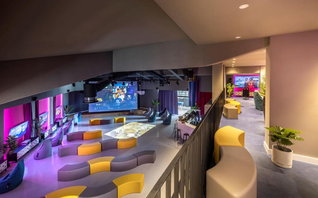 Mūsdienīga izklaides telpa ar spilgtām krāsām, daudzfunkcionālu dizainu un lielu projekcijas ekrānu, kas piemērota video spēlēm un sabiedriskām aktivitātēm. Telpa ir aprīkota ar ērtām sēdvietām un augsto tehnoloģiju ierīcēm.