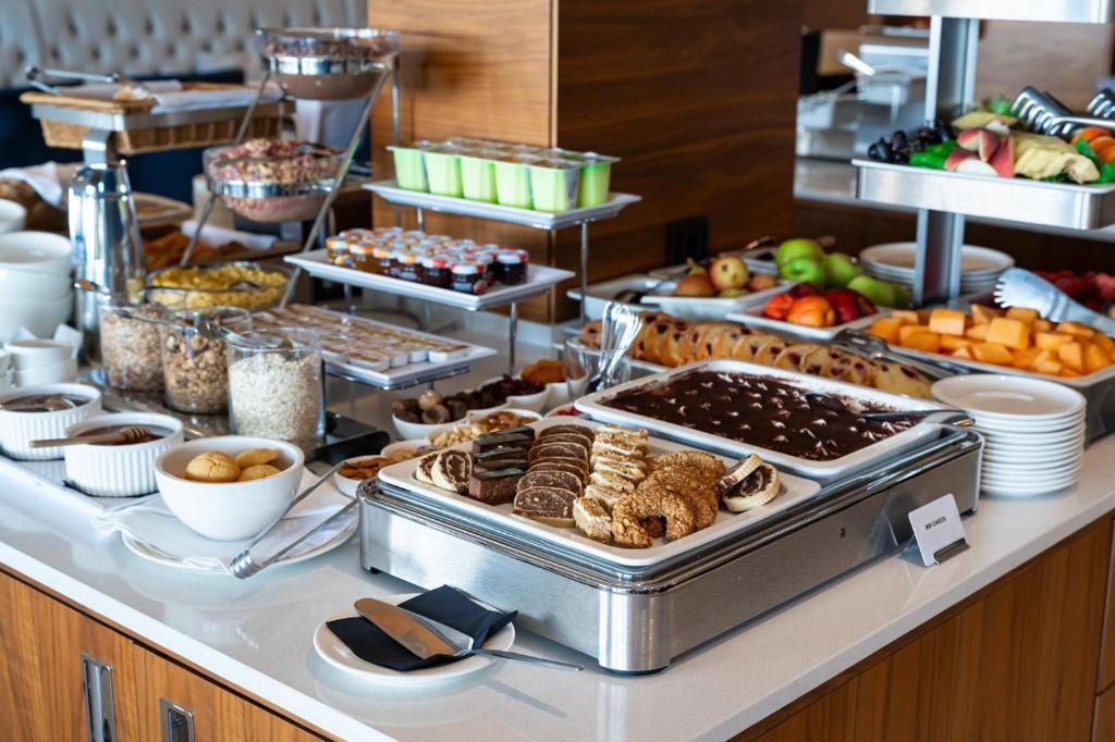 Bagātīgs brokastu bufete ar dažādiem ēdieniem, tostarp konditorejas izstrādājumiem, augļiem un graudaugiem. Ideāli piemērota gardēžiem un veselīgu izvēļu cienītājiem.