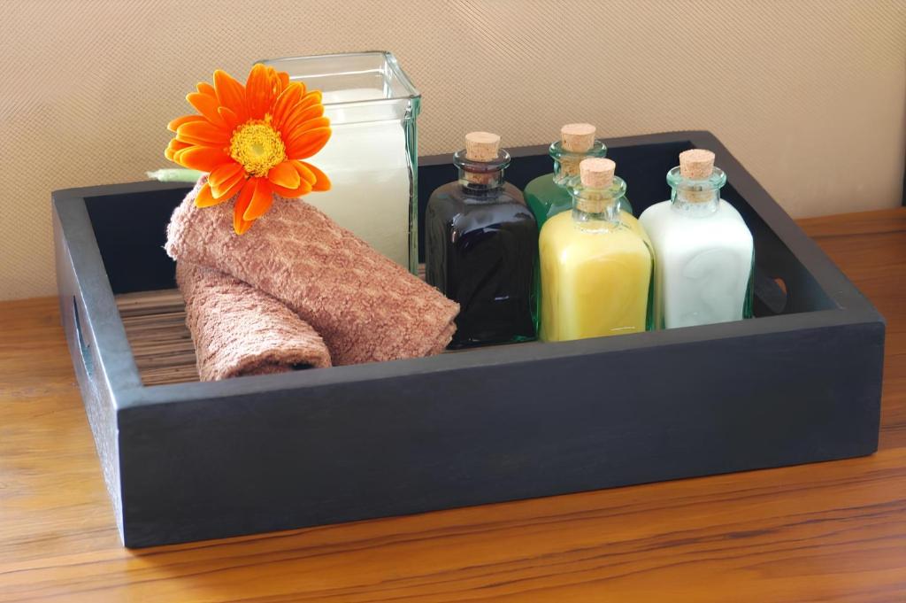 Koka trauks ar spa piederumiem, tostarp krāsainām stikla pudelēm un dvieļiem, pievienots ar ziedu dekorāciju.