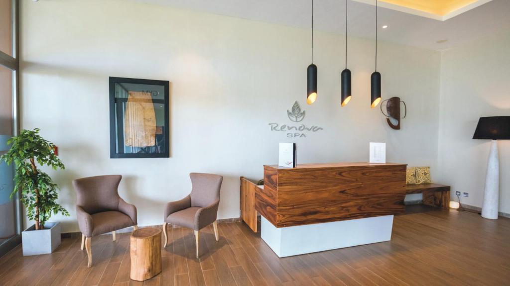 Mūsdienīgs spa reģistratūras interjers ar koka mēbelēm, ērtām krēslām un dekoratīvām lampām, radot relaksējošu atmosfēru.