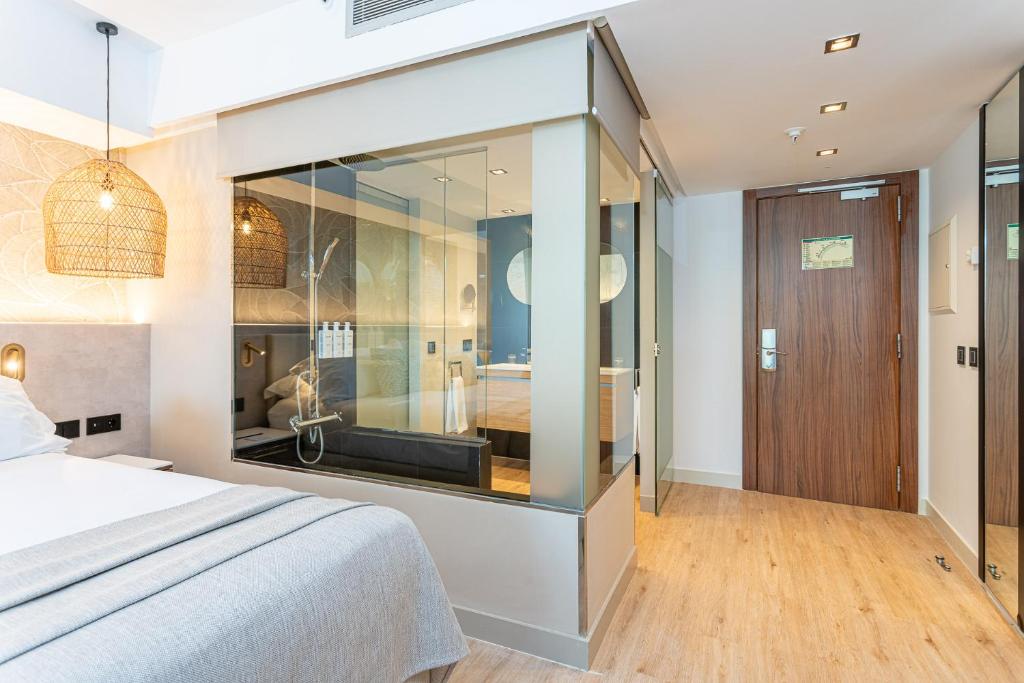 Moderns viesnīcas numurs ar stikla dušu un elegantu apgaismojumu, izceļot mājīgu atmosfēru. Interjerā ir siltas krāsas un mūsdienīgas mēbeles.