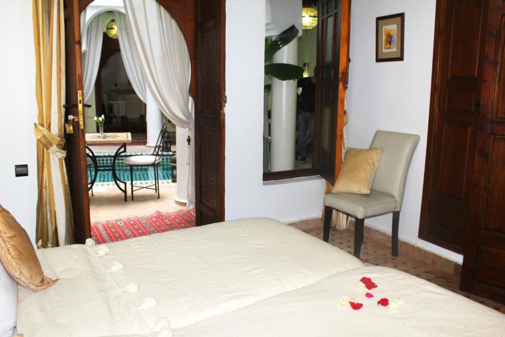 Mierīgais guļamistabas interjers ar skatu uz iekšpagalmā izvietoto galdu un krēsliem. Gultā ir ziedlapiņas, radot romantisku atmosfēru.