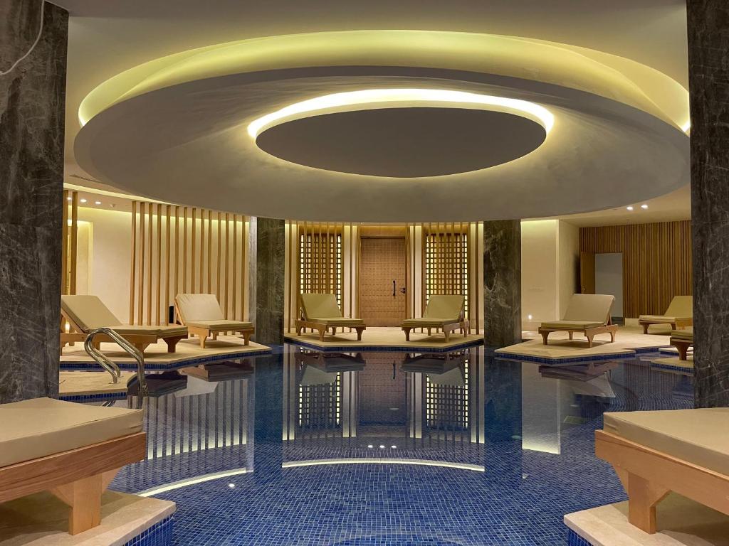 Mūsdienīgs spa ar relaksējošu atmosfēru, kurā redzami baseins un komfortabli atpūtas krēsli. Gaismas un interjera dizains rada mierīgu un atjaunojošu vidi.