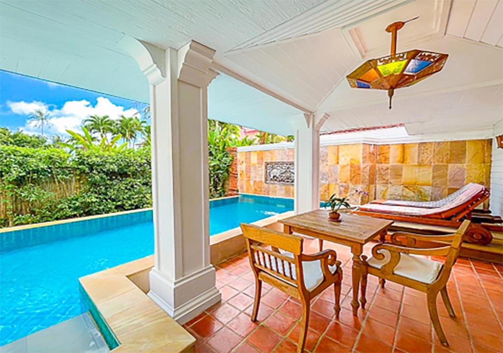 Mūsdienīgs atpūtas stūris ar privātu baseinu, koka galdu un krēsliem, apzaļumotu ainavu un saulainu debesu fonu. Ideāla vieta relaksācijai un brīvā laika pavadīšanai.