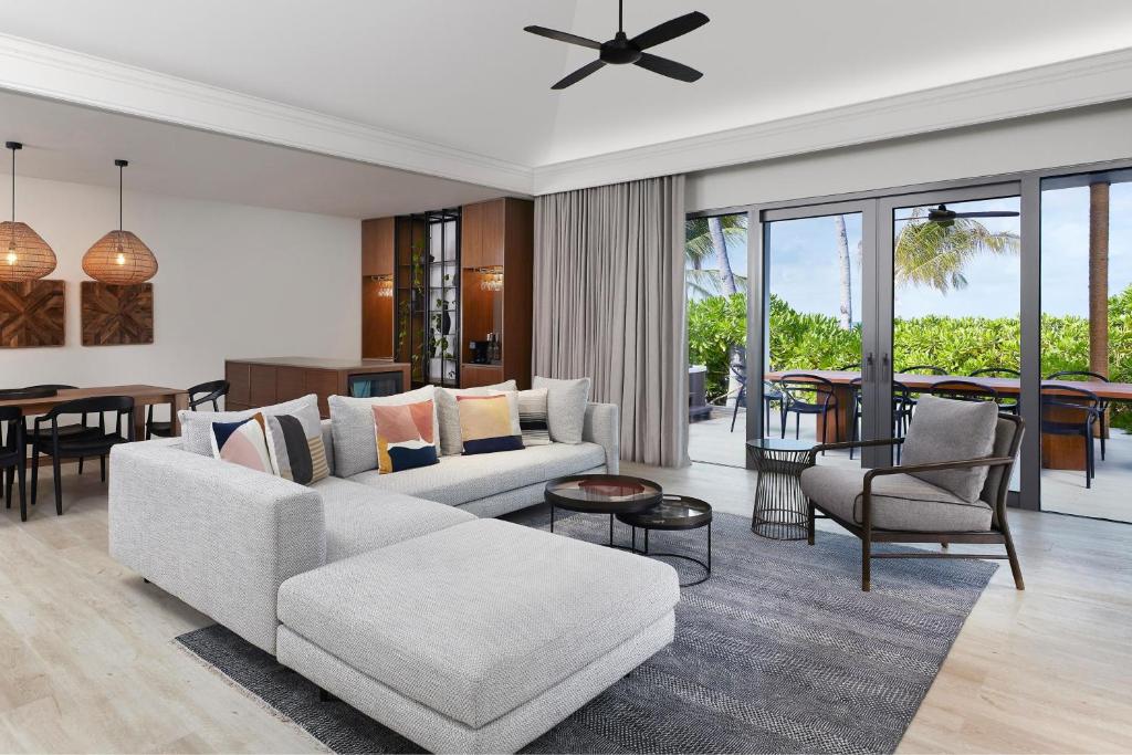 Mūsdienīgs dzīvojamās istabas interjers ar ērtu dīvānu, koka galds un krēsli, kā arī lieliem logiem, kas paver skatu uz āru. Interjers apgaismots ar stilīgām lampām un dekoratīviem elementiem.