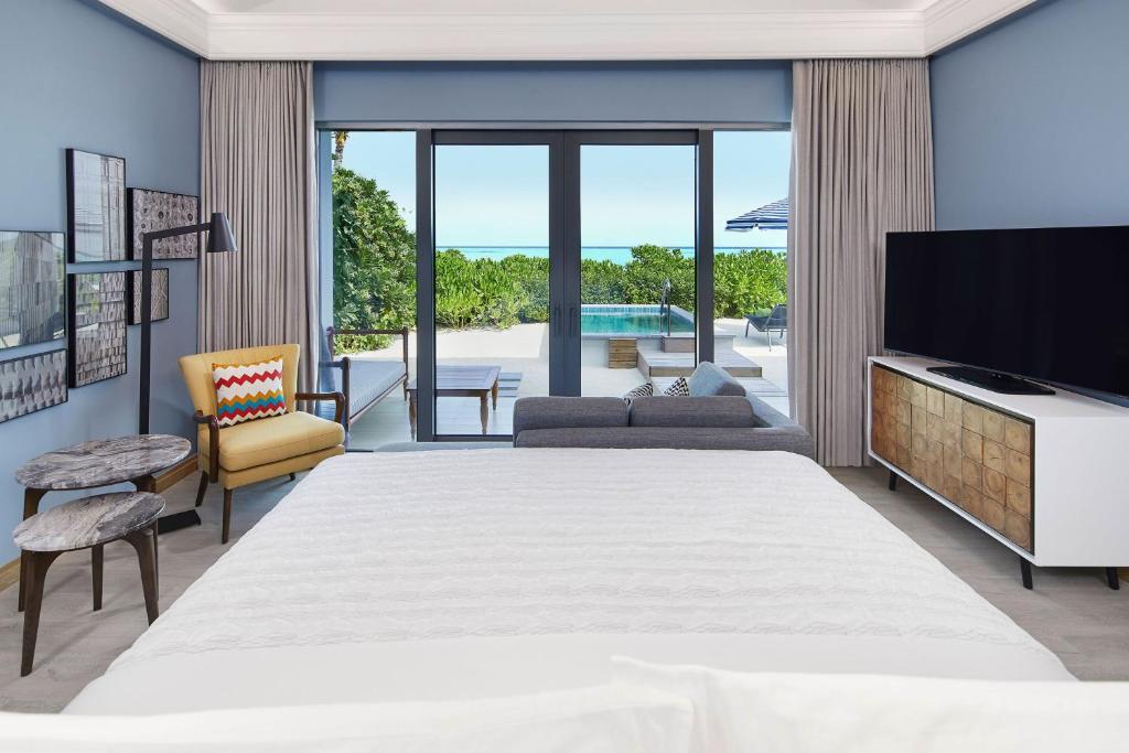 Moderns guļamistabas interjers ar skatu uz baseinu un dārzu. Telpa ir iekārtota ar stilīgu mēbeļu komplektu un gaišām krāsām.