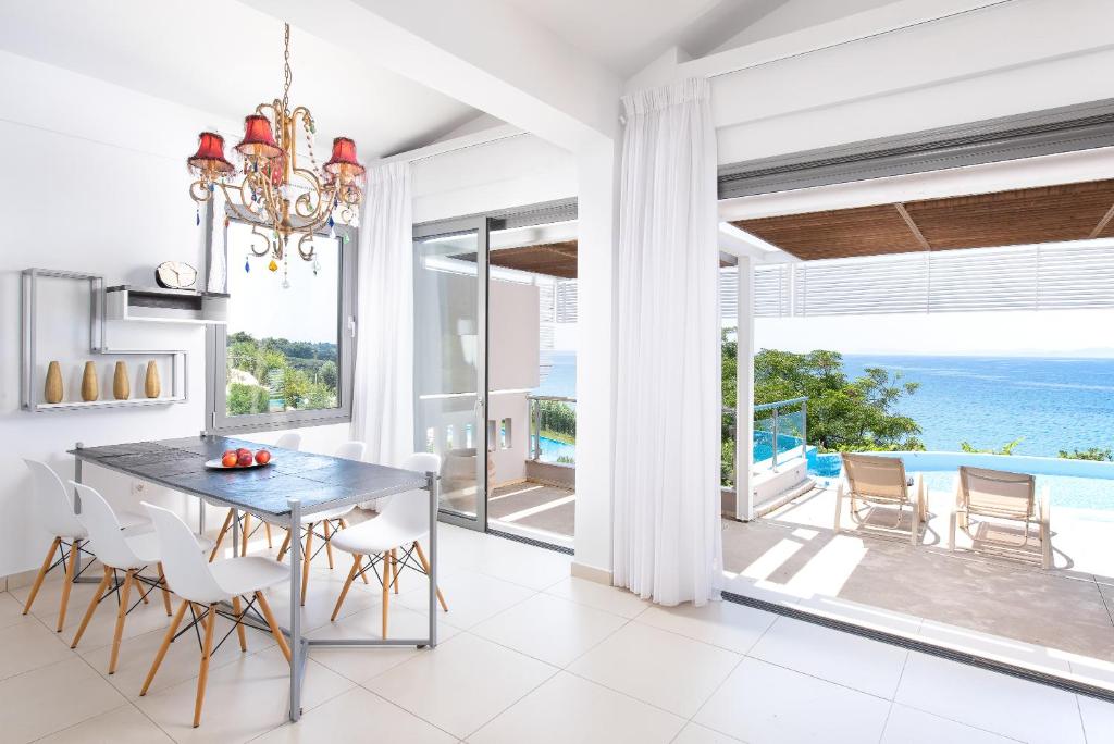 Mūsdienīgs un gaišs ēdamistabas interjers ar skatu uz jūru. Stilīga lustras gaisma un eleganta mēbeļu kombinācija rada patīkamu atmosfēru.