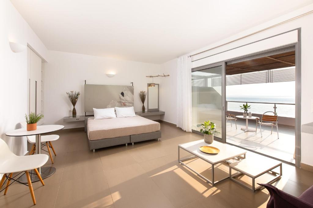 Mūsdienīga viesnīcas numura iekārtojums ar lielu gultu, ērtu atpūtas zonu un skatu uz jūru. Numurā ir eleganta mēbeļu kompozīcija un gaišas krāsas interjers.