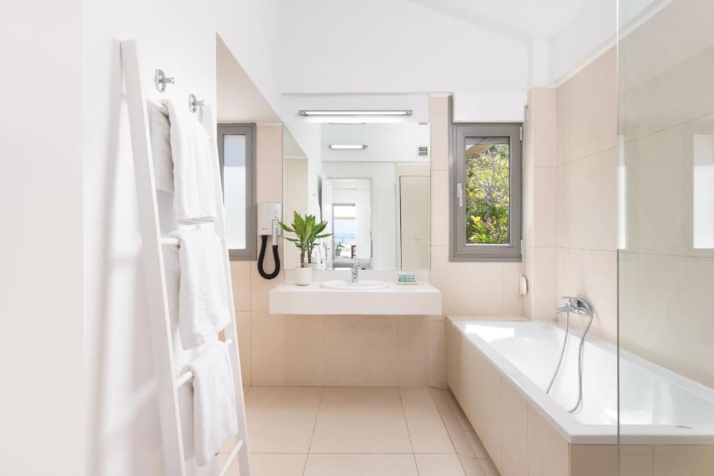 Mūsdienīgs vannas istabas interjers ar gaišām krāsām, elegantu izskatu un dabīgu apgaismojumu. Vannas istabā ir vanna, izlietne un liels spogulis ar logu, kas piedāvā skatu uz dabu.