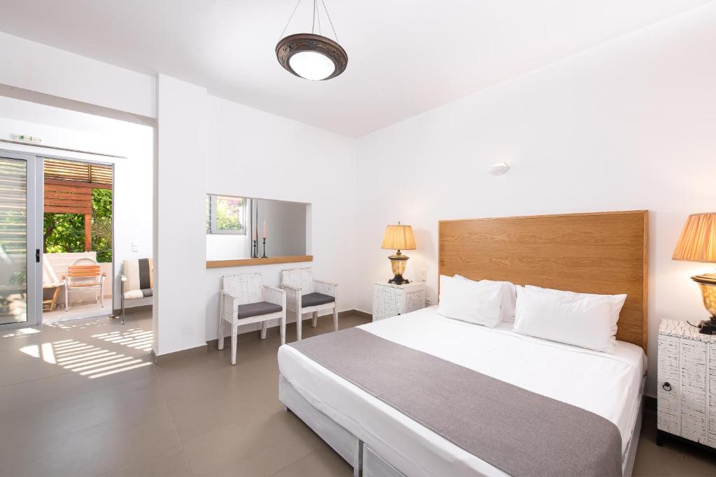 Moderns guļamistabas interjers ar gultu, naktslampām un sēdvietām, kas ved uz terasi. Gaismas un ērtības rada relaksējošu atmosfēru.