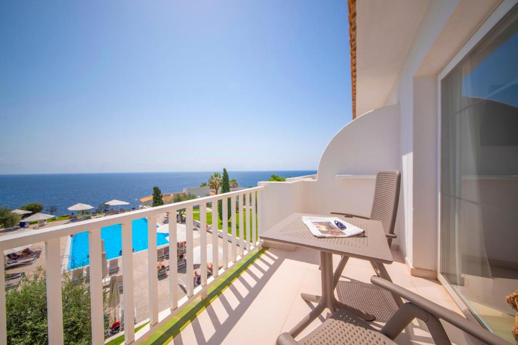 Saulaina balkona skats uz jūru, ar baseinu un sauļošanās krēsliem redzamā attālumā. Ideāla vieta atpūtai un relaksācijai.