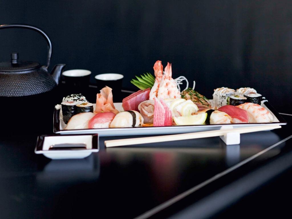 Svaigi pagatavots suši šķīvis ar dažādām suši un sashimi variācijām, kopā ar tējas kanna un glāzēm. Ideāls izvēle japāņu virtuves mīļotājiem.