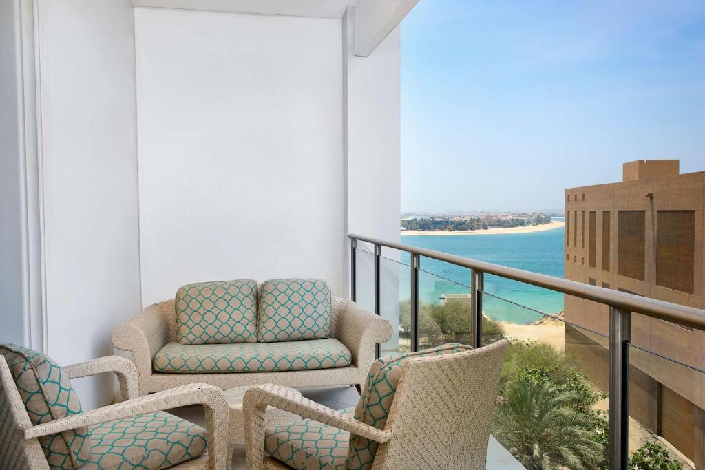 Balkons ar ērtām mēbelēm un skatu uz pludmali, radot relaksējošu atmosfēru. Gaismas un jūras krāsu kombinācija nodrošina patīkamu vidi atpūtai.